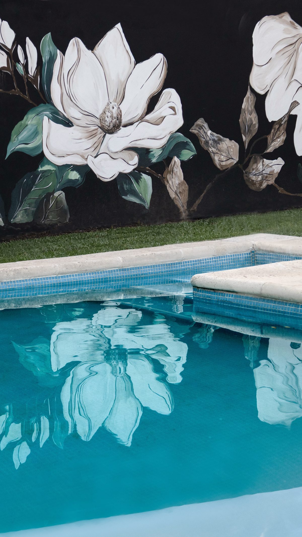 Mural de magnolias blancas reflejado en pileta