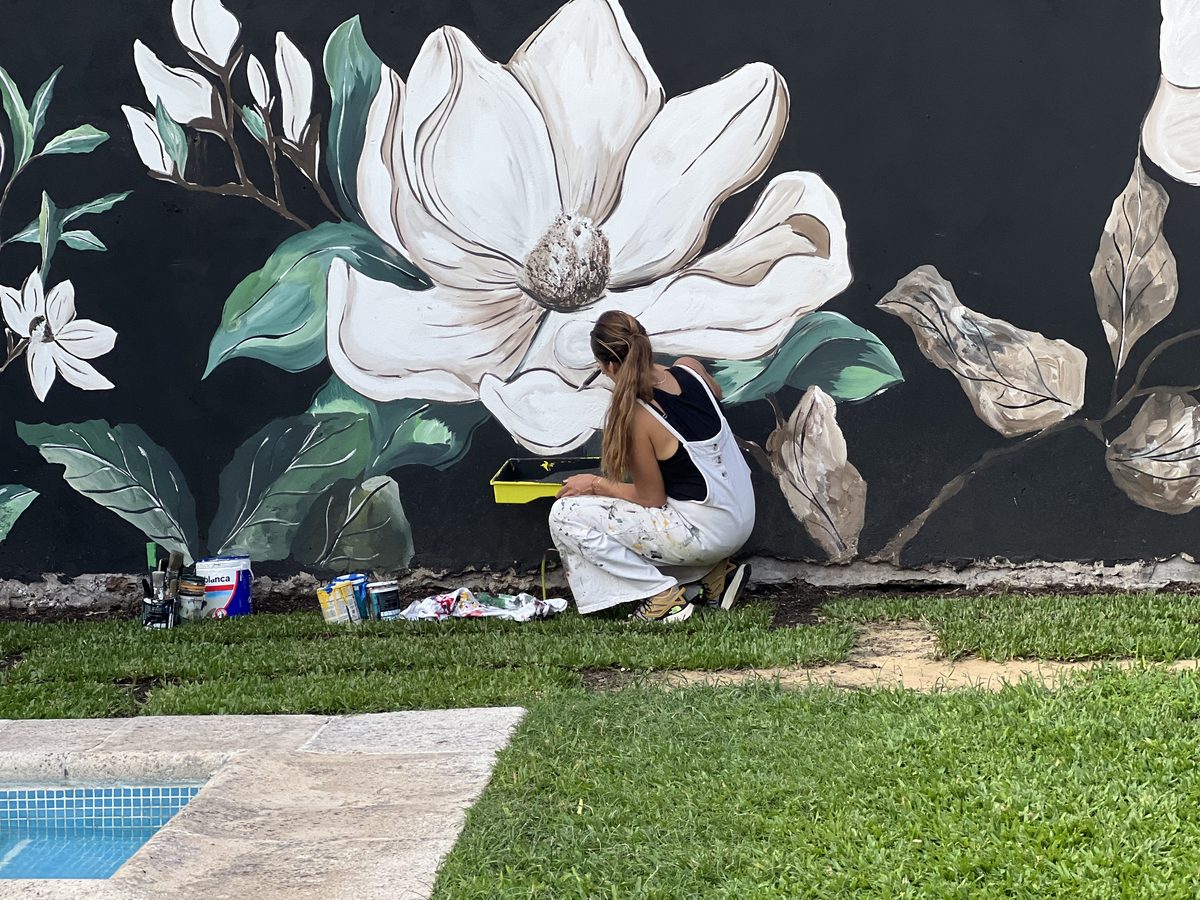 Florencia pintando mural de magnolias en exterior